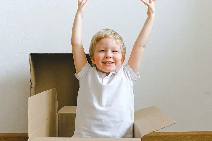 Garçon souriant portant un t-shirt blanc à l'intérieur d'une boîte