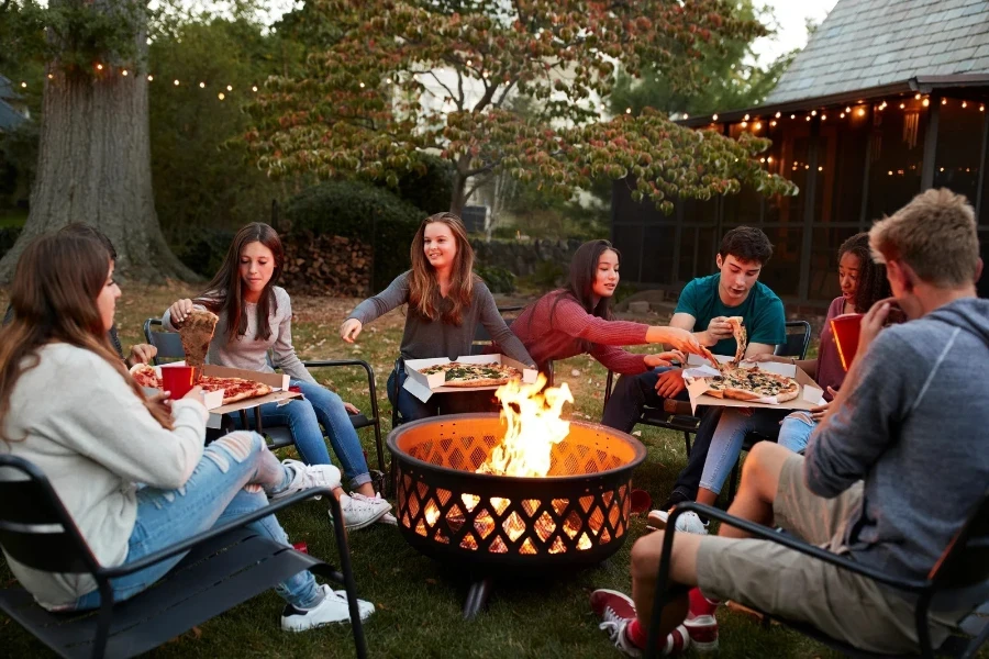 Teenage friends sit around a fire pit