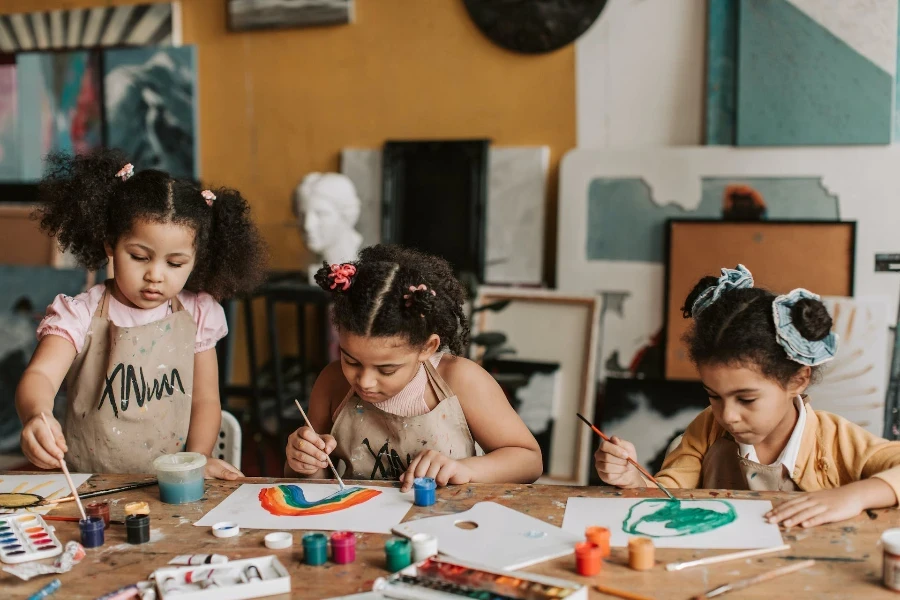 Três meninas pintando em papel de desenho