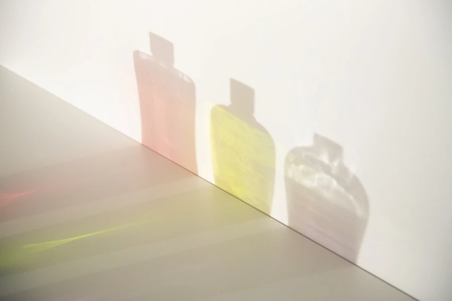 three shadows of colorful creams in bottles