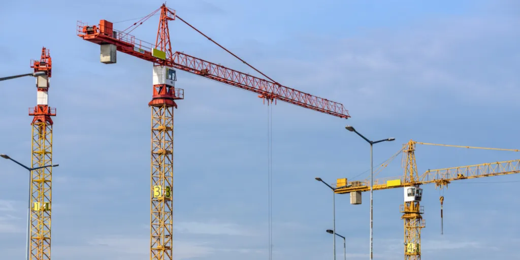 tower cranes over a construction site against blue sky