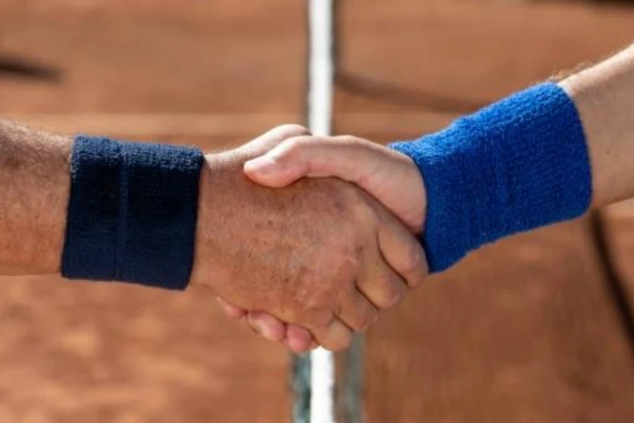 two men wearing sports wristbands shaking hands