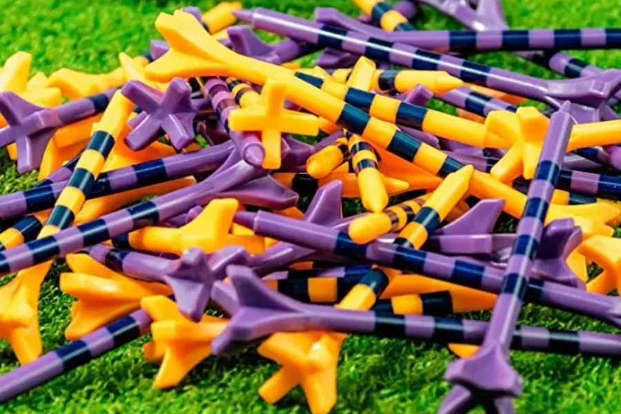 Various purple and orange zero friction golf tees on grass