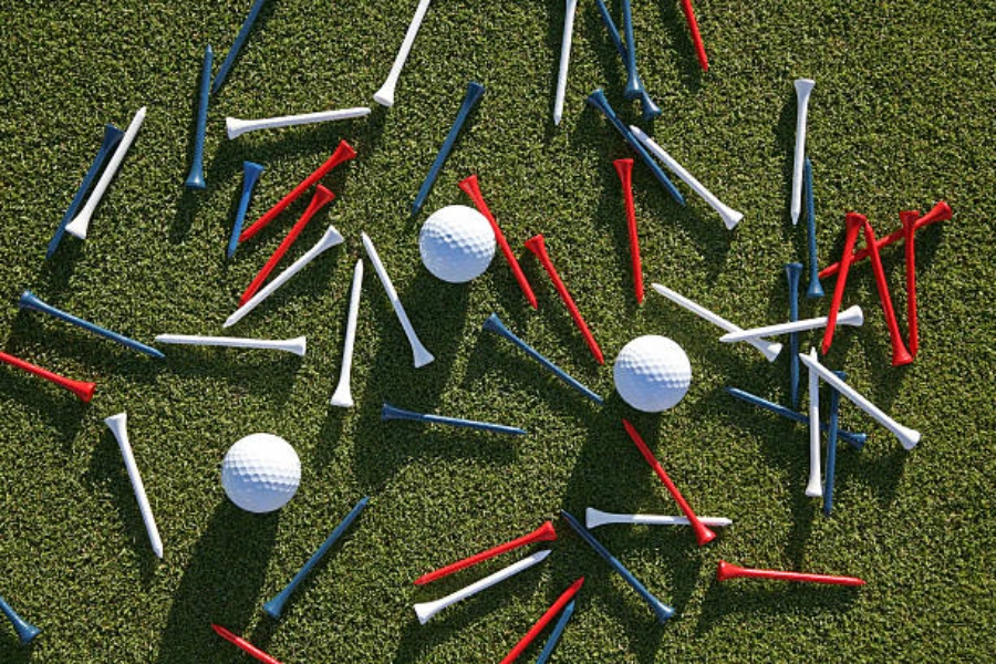 White, blue, and red golf tees laying between golf balls