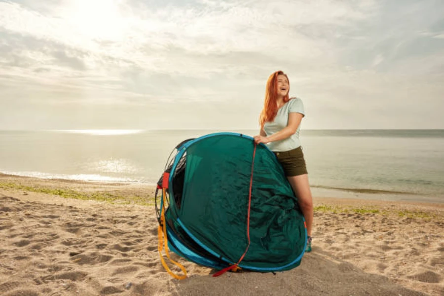 woman about to open pop up shower tent on beach