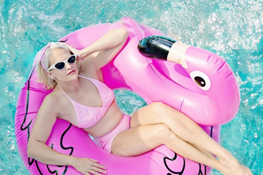 Woman in a flamingo-shaped float relaxing in a swimming pool
