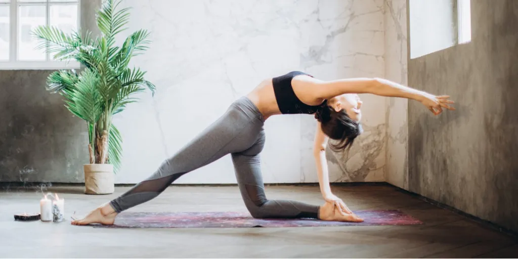 woman in gray leggings doing yoga on yoga mat