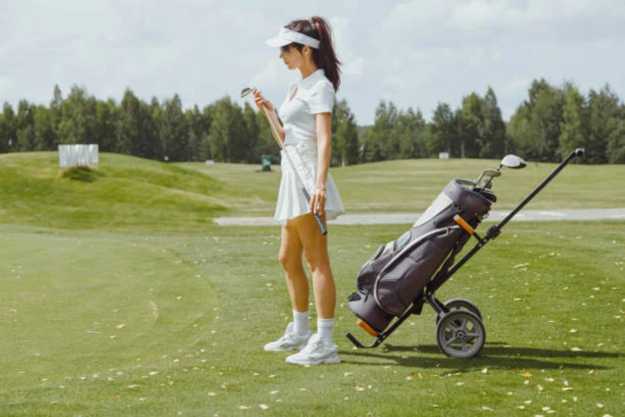 Woman standing on green next to manual pull cart