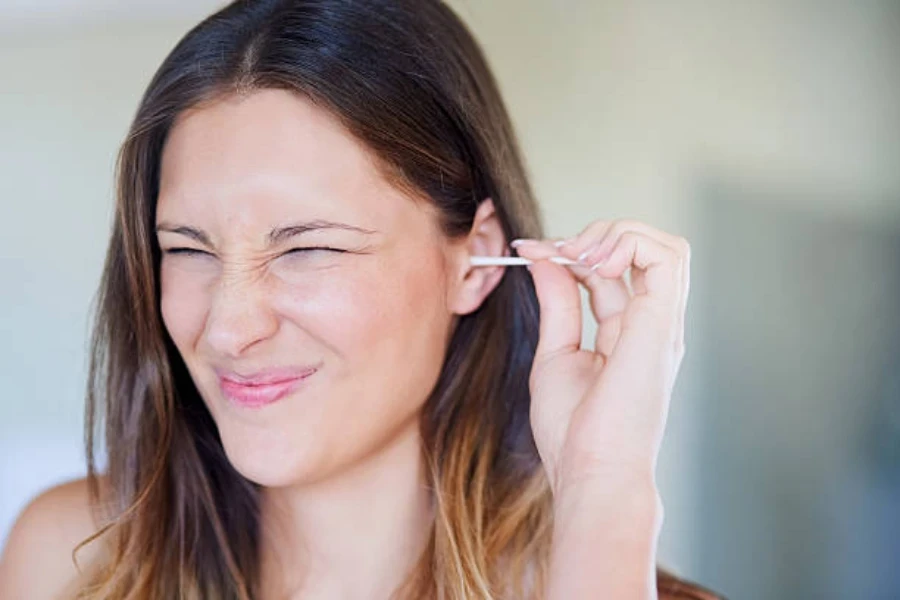 Jeune femme nettoyant son oreille avec des cotons-tiges