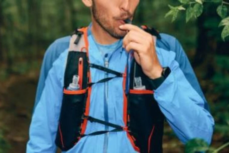 Junger Mann trinkt Wasser aus einem Trinkrucksack