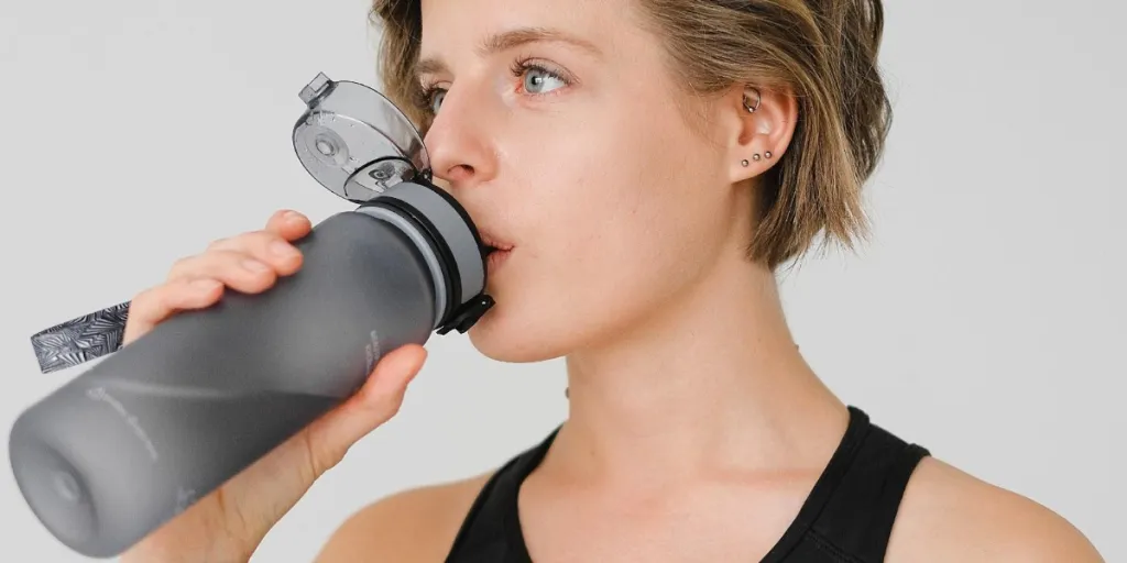 young woman drinking water from a sports bottle