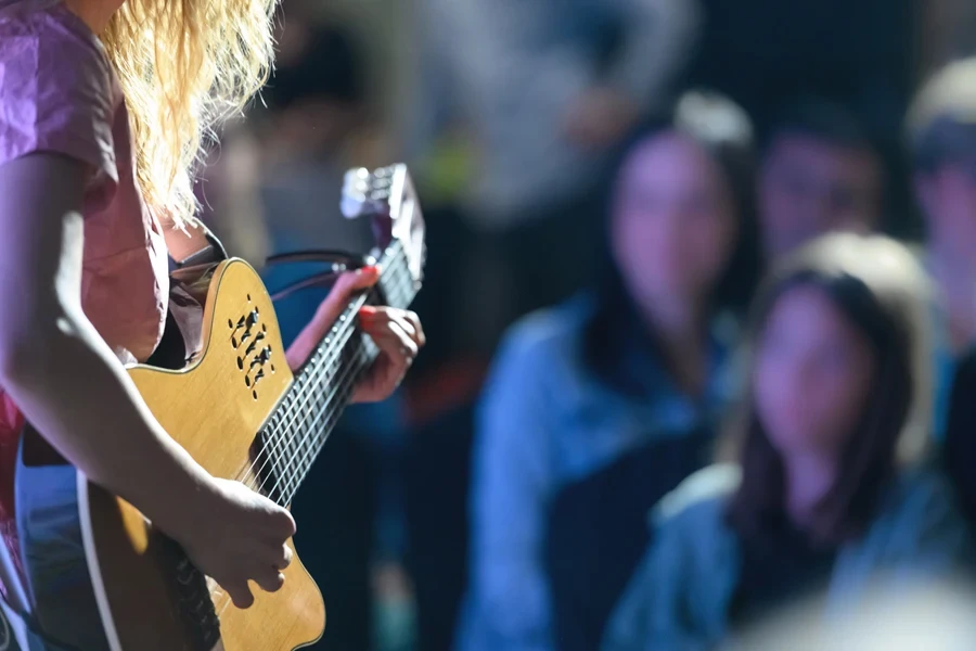 Woman on stage playing electric guitar to younger generations