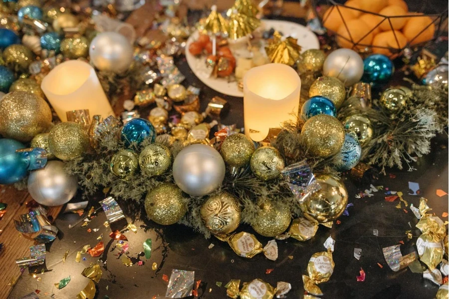 Una vela y bolas navideñas sobre una mesa.