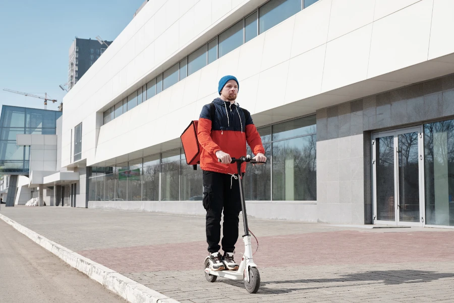 A delivery man riding a white e-scooter