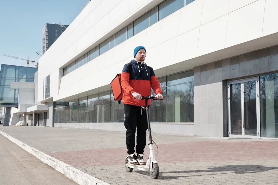 Un livreur chevauchant un scooter électrique blanc