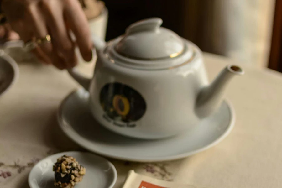 a hand holding a tea pot on the table