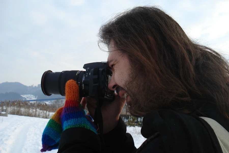 A man filming with a camera in a snowy landscape