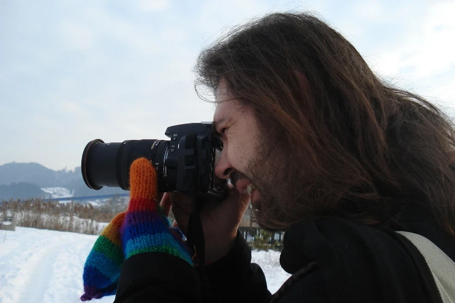 Un uomo filma con una telecamera in un paesaggio innevato