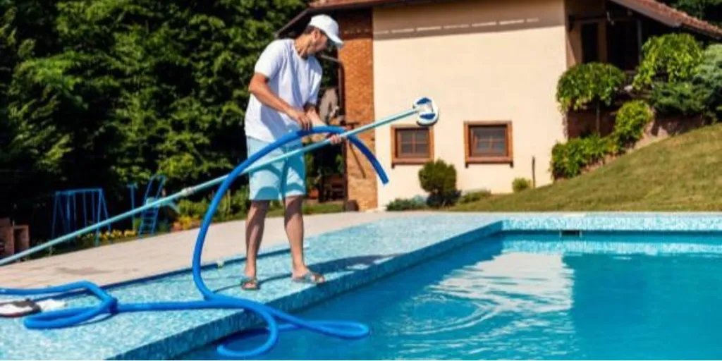 A man in a white shirt using a pool cleaning tool