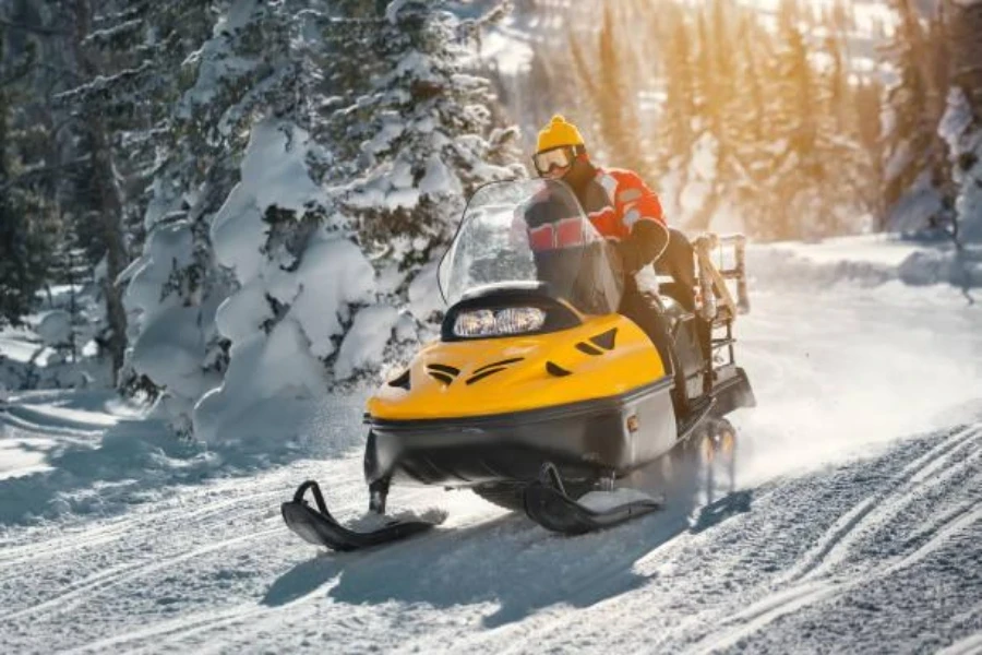 Un hombre bajando una montaña en una moto de nieve de gira