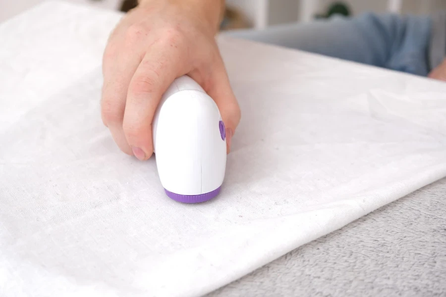 A man using a rechargeable lint shaver to shave a fabric