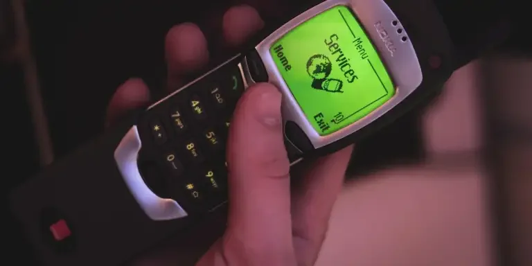 A person holding a dumb phone with a green display
