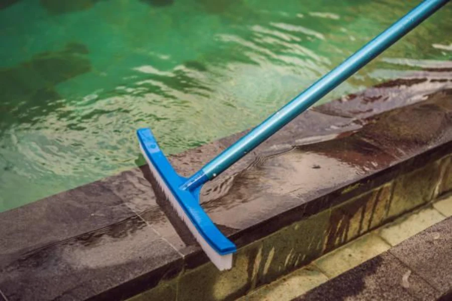 A pool brush being used to wash pool tiles