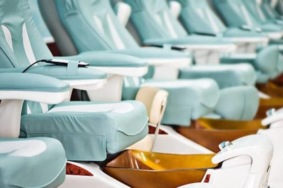 A row of teal-colored pedicure chairs