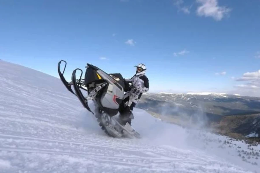 Um trenó andando em um snowmobile de montanha em uma colina nevada