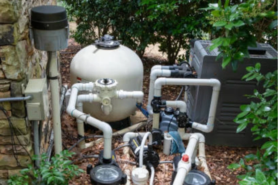 A white swimming pool pump in the middle of plants