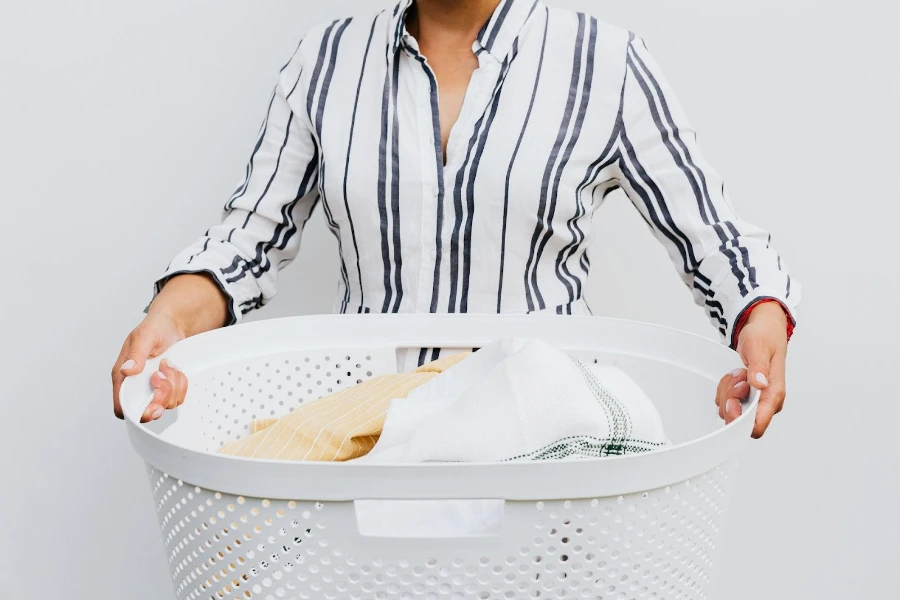 A woman holding a white laundry hamper