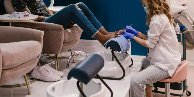 A woman sitting in a pedicure chair receiving toenail treatment