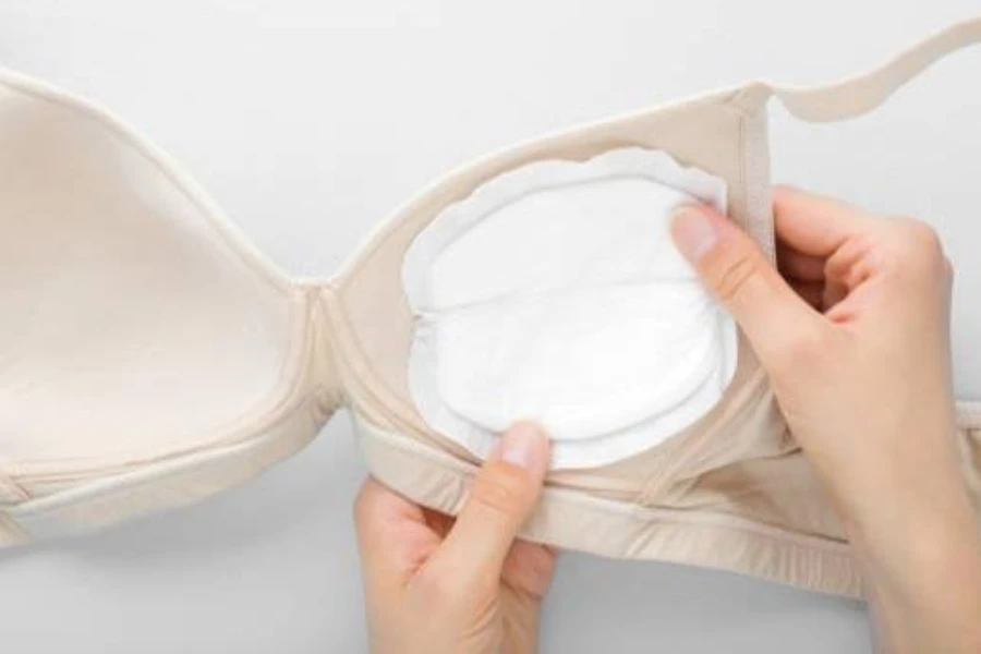 A woman testing the coverage of a nursing pad in a bra cup