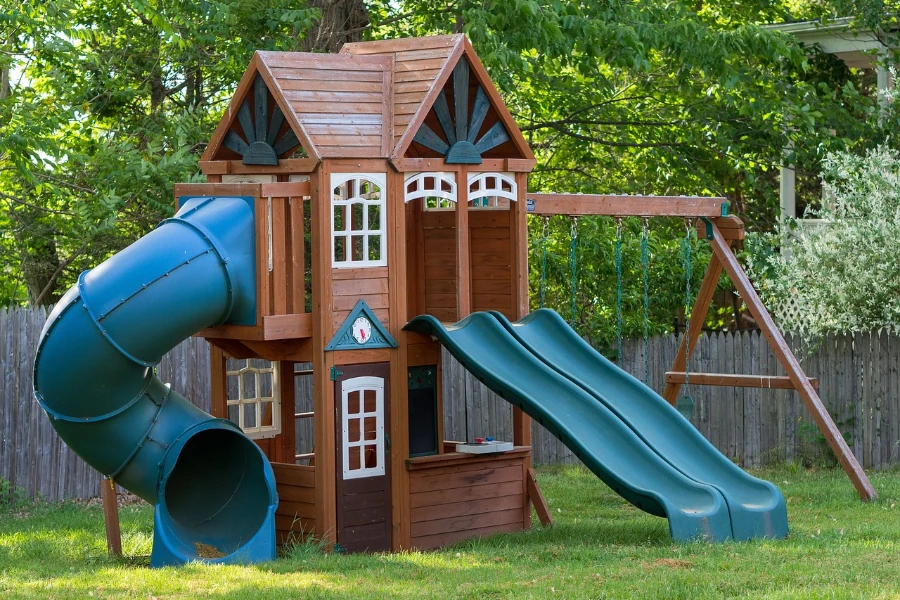 An outdoor playhouse with swing and slides