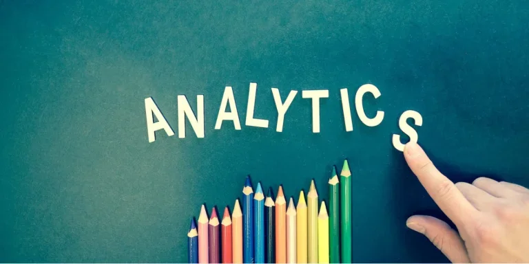 Analytics on a blue background with coloured pencils below
