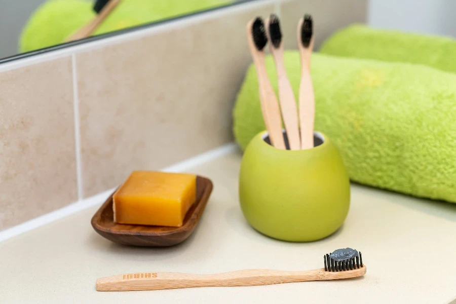 escovas de dentes de bambu em um porta-escovas verde no balcão do banheiro