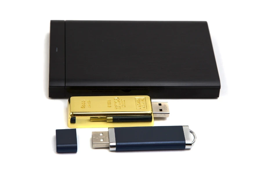 Hard drive hitam, flash drive emas, dan flash drive biru