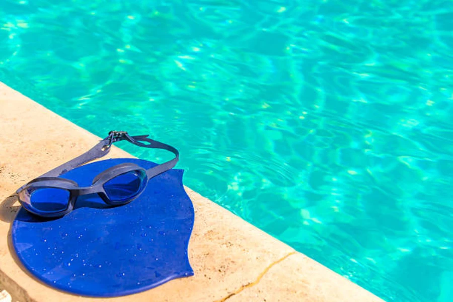 Blue swimming cap with goggles sitting next to pool