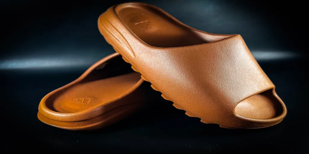 Brown Adidas recovery slides on a black background