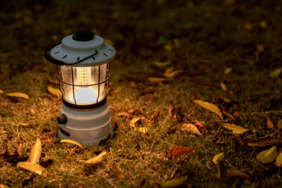 Camping lantern lit up at night sitting on grassy ground
