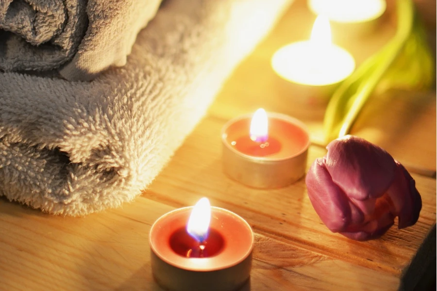 Candles lit beside towels and flowers
