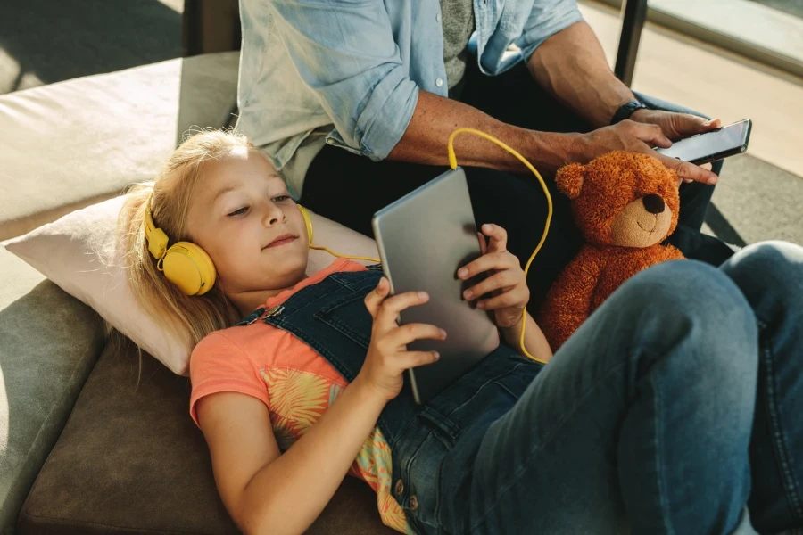 Child lying on the floor in the airport watching something on a tablet