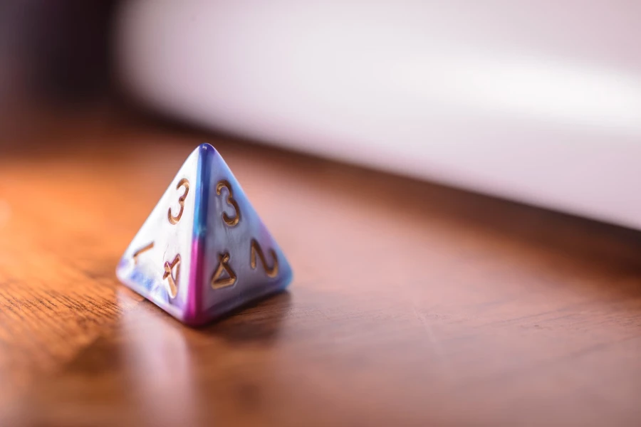 D4 die in multiple colors sitting on a wooden table