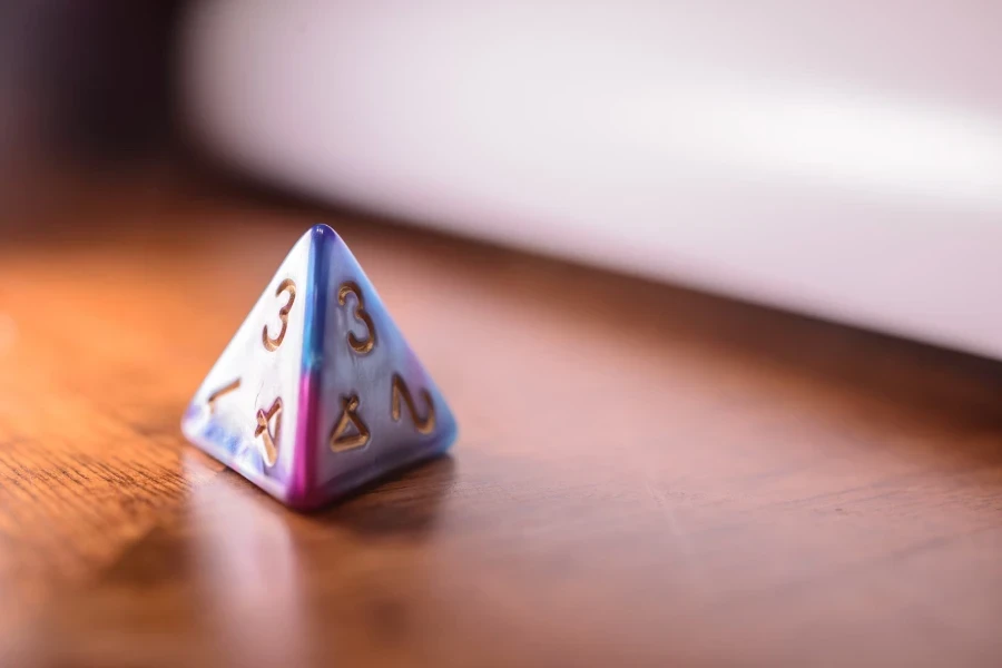 D4 die in multiple colors sitting on a wooden table