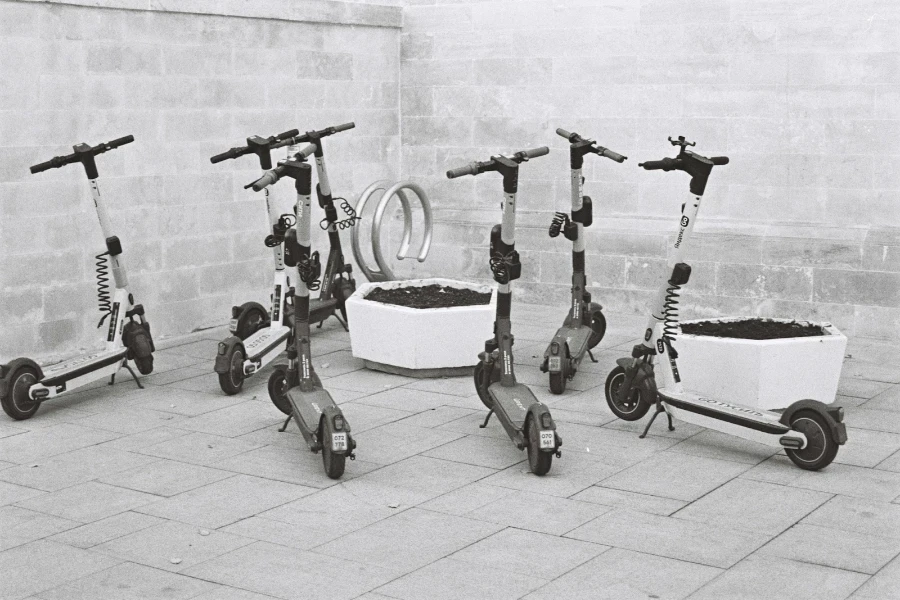 Different e-scooters parked together near planters