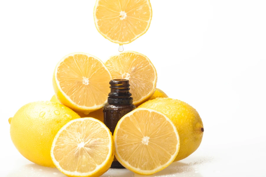 Dripping citrus essential oil into a bottle on white background