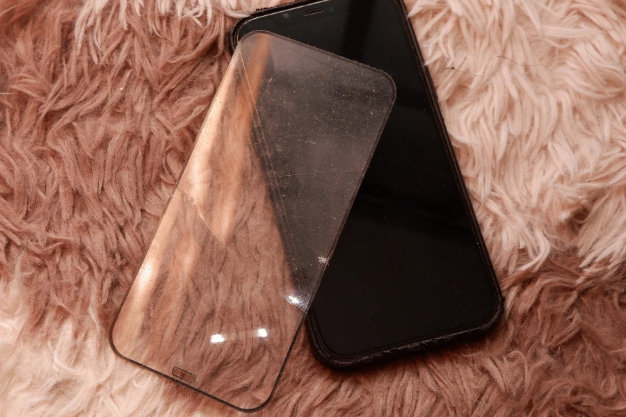 Edge-to-edge screen protector and black phone laying on rug