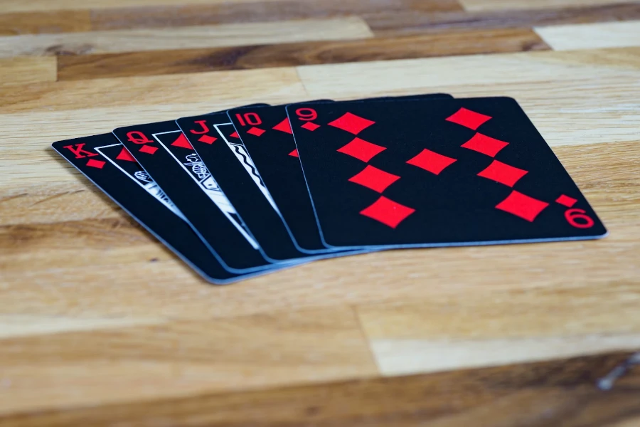 Five black and red plastic playing cards sitting on table