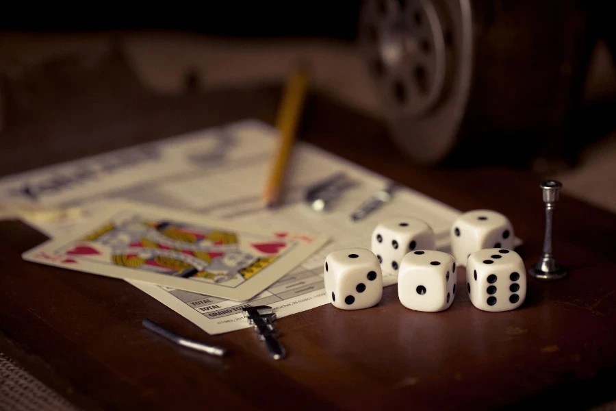 Five six-sided dice sitting next to a playing card