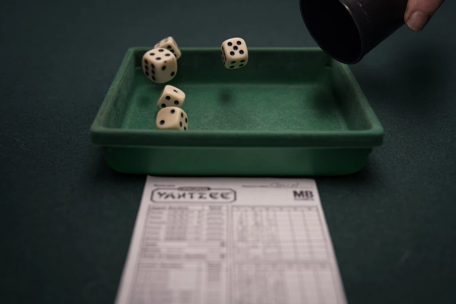 Four six-sided dice being thrown into a green bowl